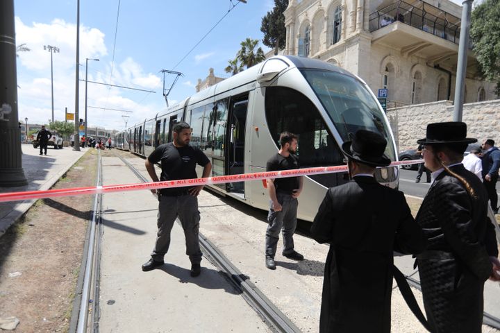 Israeli policemen block a road where the light train passes.
