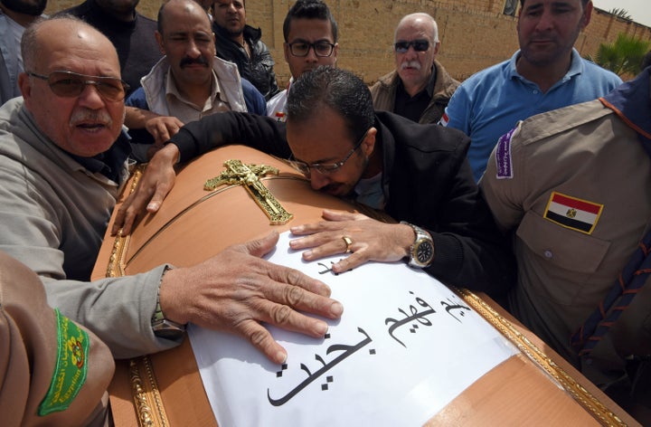 Men mourn over the coffin of one victim of the blast at the Coptic Christian Saint Mark's church in Alexandria, Egypt, the pr