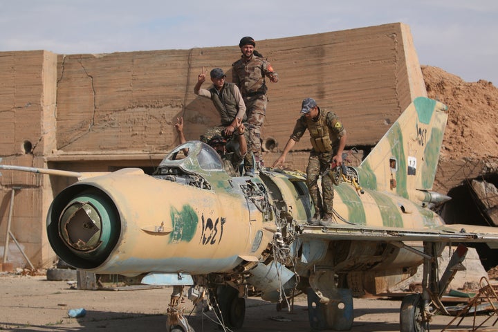 Fighters of the Syrian Democratic Forces pose on a damaged airplane inside Tabqa military airport after seizing it from