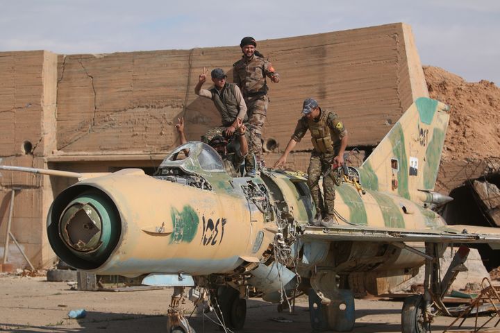 Fighters of the Syrian Democratic Forces pose on a damaged airplane inside Tabqa military airport after seizing it from Islamic State fighters on April 9, 2017.