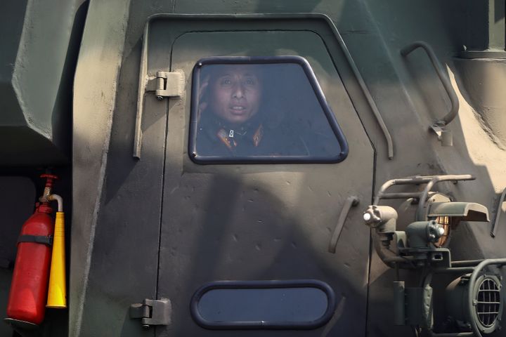 A soldier salutes from inside a vehicle carrying a missile as it drives past the stand with North Korean leader Kim Jong Un