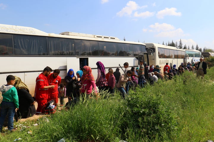 People who were evacuated from the two villages of Kefraya and al-Foua walk near buses, after a stall in an agreement between rebels and Syria's army, at insurgent-held al-Rashideen, Aleppo province, Syria on April 15, 2017.