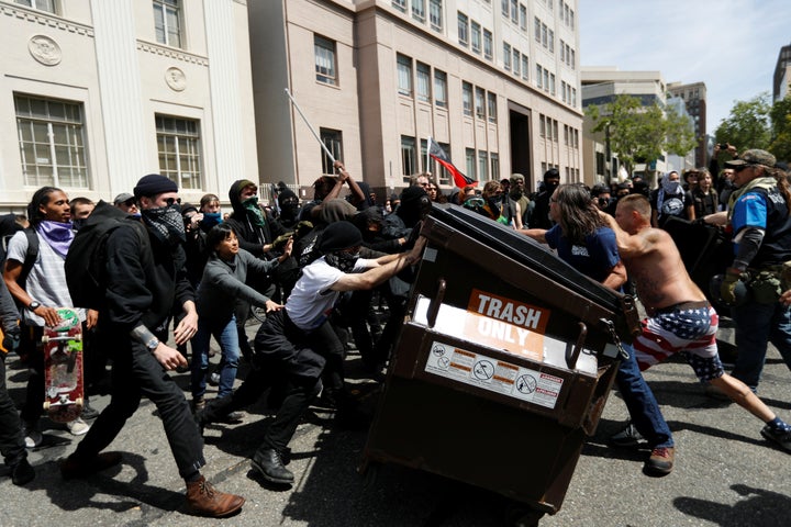 Demonstrators for (R) and against (L) U.S. President Donald Trump push a garbage container toward each other during a rally in Berkeley, California in Berkeley, California, U.S., April 15, 2017.