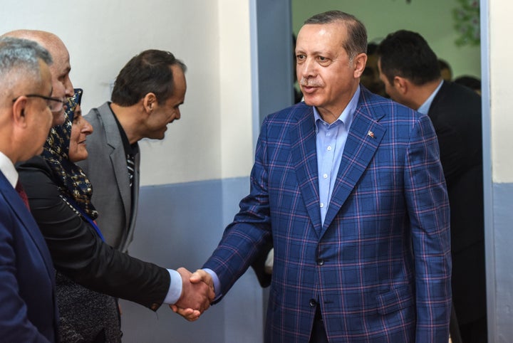 Turkish President Recep Tayyip Erdogan salutes official as he arrives at a polling station to vote in the referendum on expan