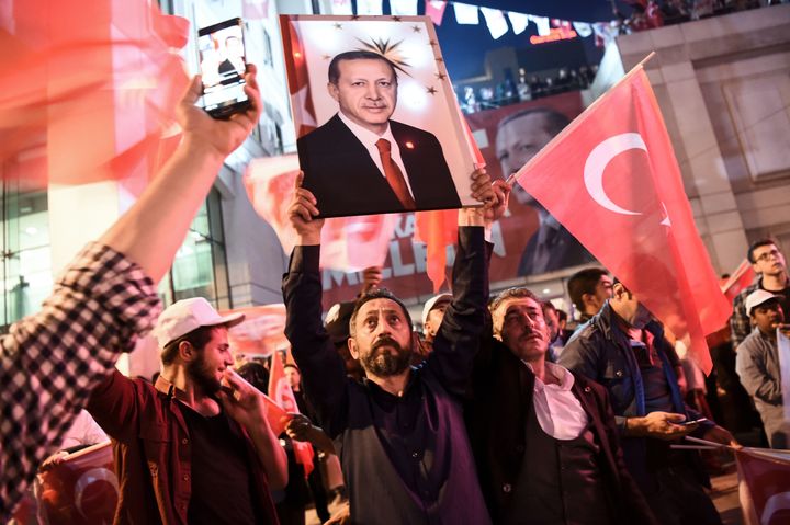 A supporter of the 'yes' brandishes a picture of Turkish president Recep Tayyip Erdogan among other supporters waving Turkish national flags during a rally on Sunday