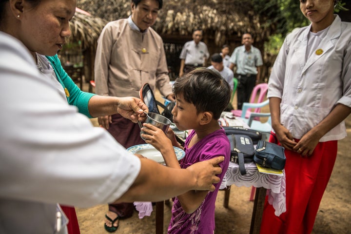 A child in Myanmar drinks water to help her swallow her dose of the post-exposure prophylaxis, Rifampicin. 