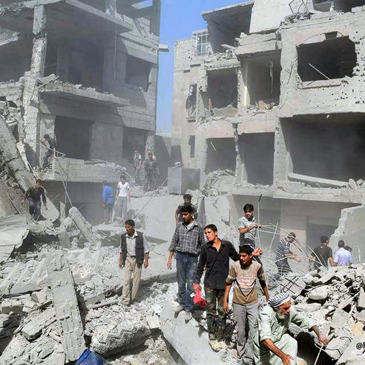 This photo released by the Douma Revolution News Network on their Facebook page, shows Syrians looking for bodies under debris of destroyed buildings following a Syrian government airstrike on the Damascus suburb of Douma, Syria, Saturday, Aug. 22, 2015 