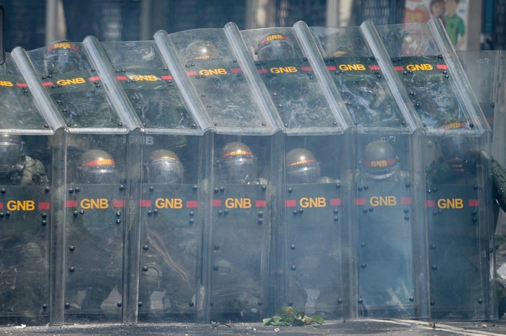 Riot police officers confront demonstrators in Caracas. 