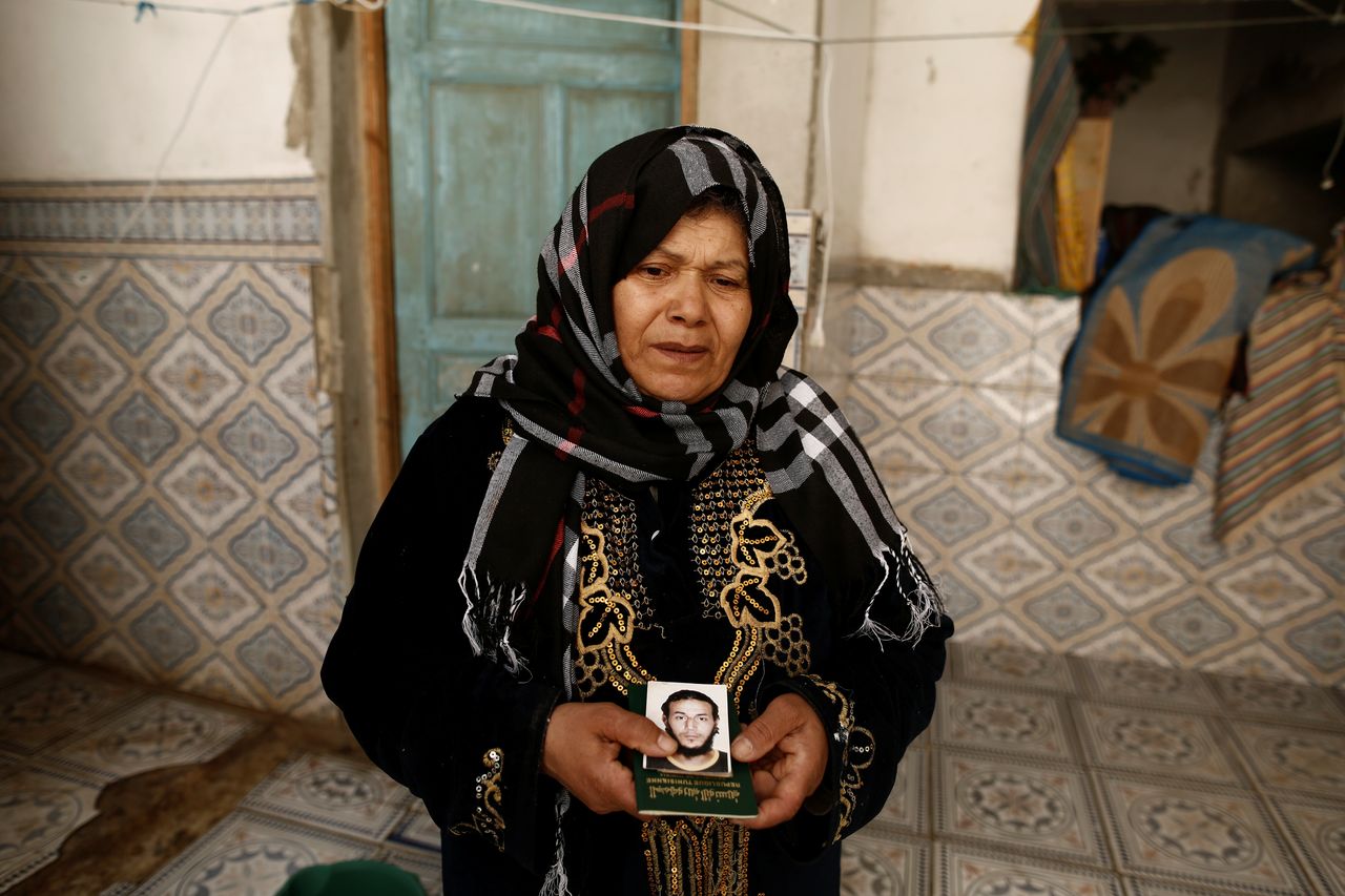 A Tunisian woman holds a photo and passport of her son, who is suspected of joining ISIS in Libya.