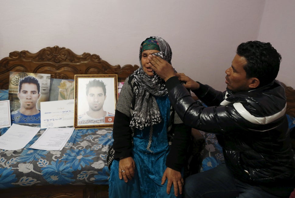 A young man wipes away his mother's tears as she mourns the death of her son, who took his own life after being refused a job