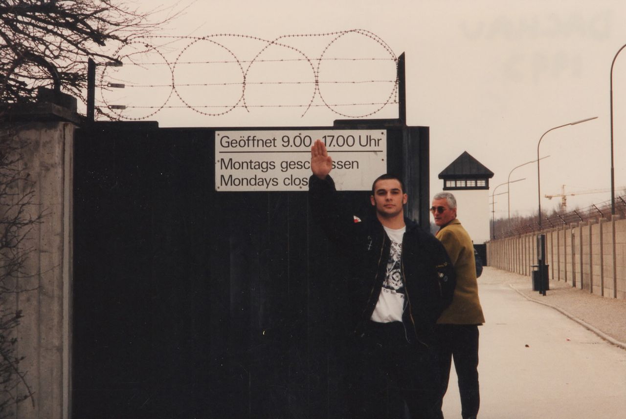Christian Picciolini doing a Nazi salute outside the gates of Dachau, a former concentration camp in Nazi Germany, in 1992