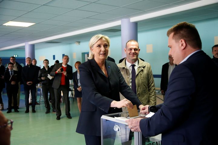 Marine Le Pen (C), French National Front (FN) political party leader and candidate for French 2017 presidential election, casts her ballot in the first round of 2017 French presidential election at a polling station in Henin-Beaumont, northern France, April 23, 2017. At R, Mayor of Henin-Beaumont Steeve Briois (REUTERS/Charles Platiau)