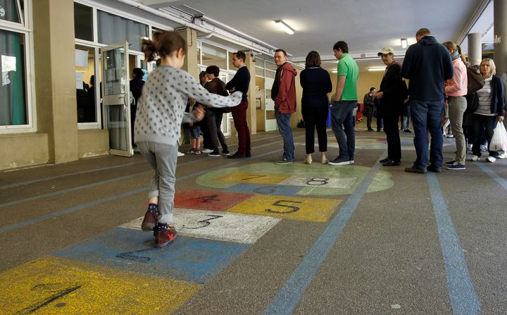 A girl plays hopscotch as people line up to vote in the first round of 2017 French presidential election at a polling station in Marseille, France, April 23, 2017. (REUTERS/Philippe Laurenson)