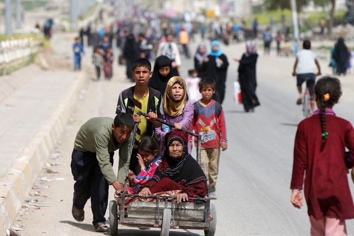 Displaced Iraqis push a wheelbarrow carrying a woman as they flee after a battle between the Iraqi Counter Terrorism Service and Islamic State militants in western Mosul, Iraq, April 22, 2017.