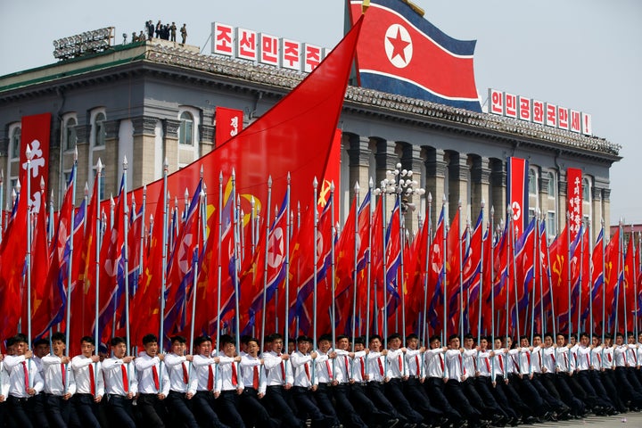Men carry flags in front of the stand with North Korean leader Kim Jong Un and other high ranking officials during a military