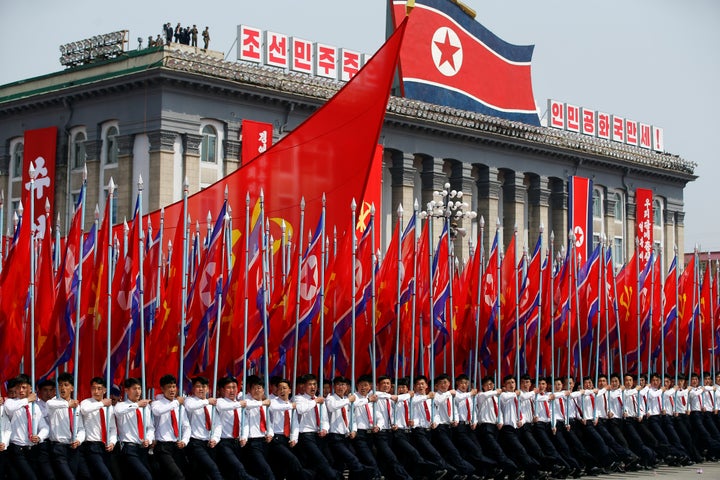 Men carry flags in front of the stand with North Korean leader Kim Jong Un and other high ranking officials during a military parade marking the 105th birth anniversary of the country's founding father, Kim Il Sung. 