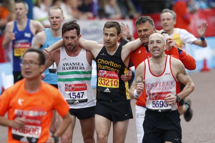 Matthew Rees of Swansea Harriers helps David Wyeth of Chorlton Runners reach the finish line during the London marathon.