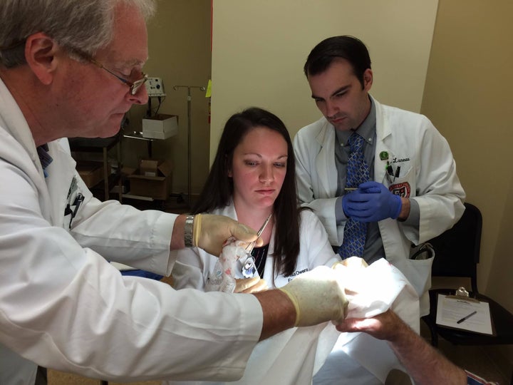 Jenisus Owens (center), a first-year medical resident in rural Meridian, Mississippi, learns how to stitch a hand wound. Rural residency programs across the country may lose federal funding on Oct. 1.