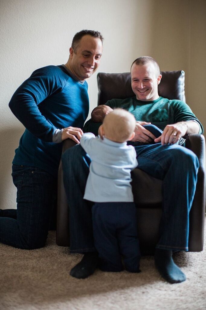 Burke sitting holding Cody, and Justin kneeling smiling at Caleb