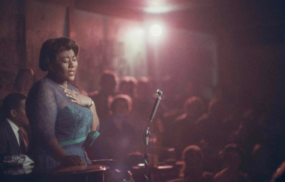 Bathed in red light, Ella Fitzgerald performs with her eyes closed at Mr. Kelly’s nightclub in Chicago, 1958.