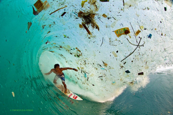 Photographer Zak Noyle captures a surfer riding a trash-filled wave in waters off the coast of Java, Indonesia.