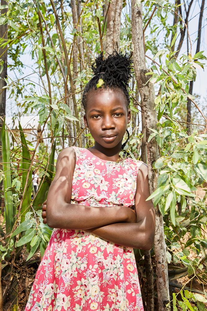 Maureen (11) poses in the garden next to her gowelo, Thyolo District, Malawi, 2016.