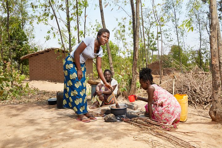 Sisters Gertrude (16), Elisa (14) and Maureen (11) cook in the courtyard of their gowelo, Thyolo District, Malawi, 2016. 