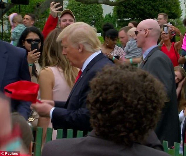 The President signs a young man’s hat before inexplicably tossing it into the onlooking crowd at White House Easter Egg Roll on April 17, 2017.