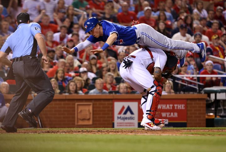 Toronto Blue Jays' Chris Coghlan scores by leaping over St. Louis Cardinals catcher Yadier Molina in the seventh inning.