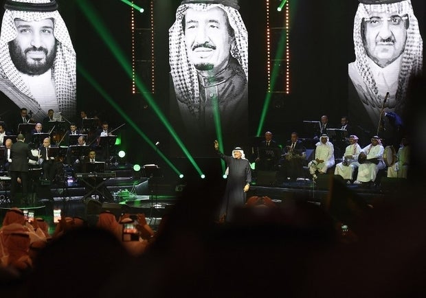 Saudi singer Mohammed Abdu - known as Saudi's 'Paul McCartney - performs in Riyadh in March 2017 with Mohammed bin Salman, King Salman and Mohammed bin Nayef projected in the background (AFP)