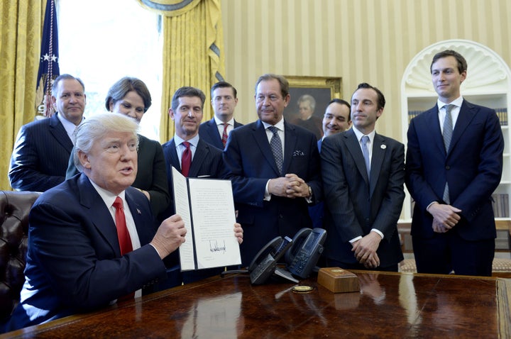 President Donald Trump holds up a signed executive order as business leaders stand in the Oval Office on Feb. 24, 2017. Food safety advocates are concerned about deregulation.