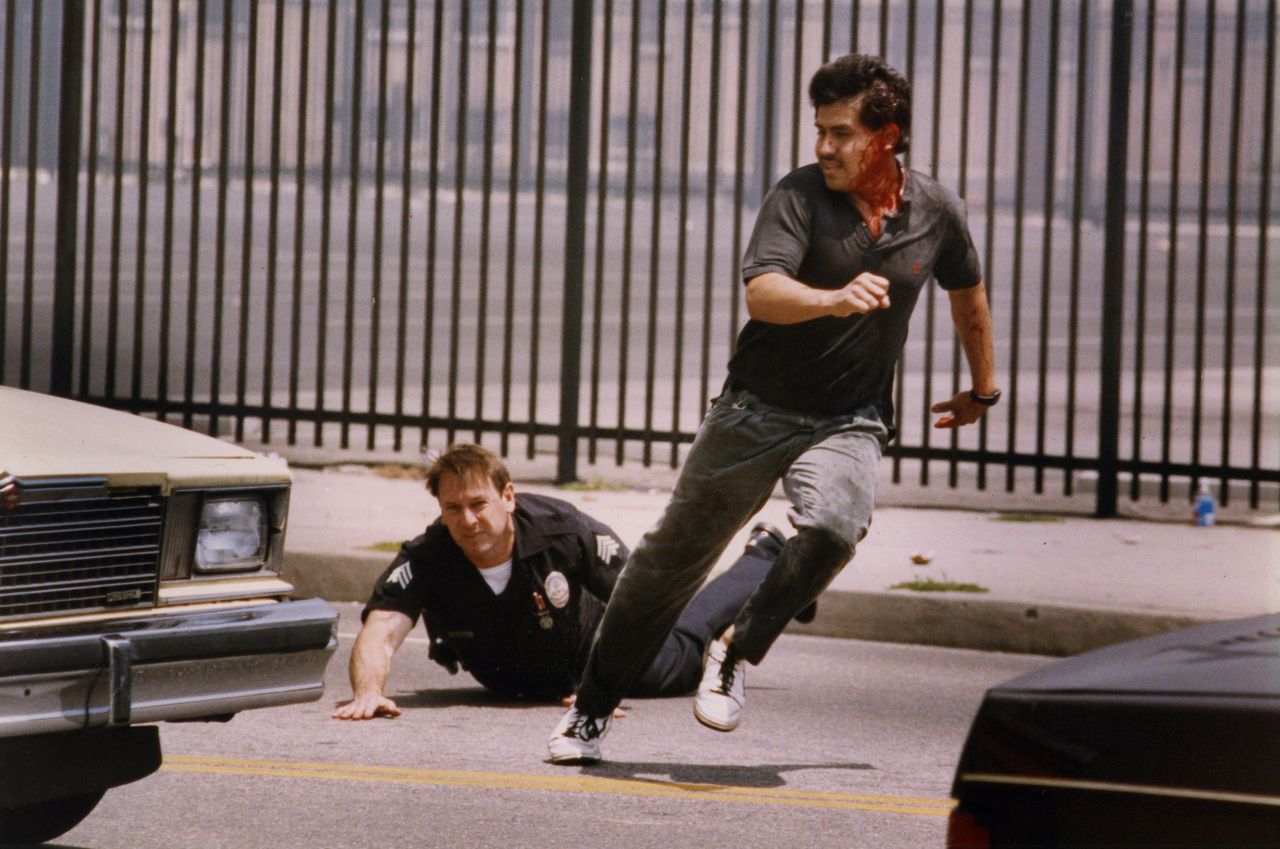 An LAPD officer falls while chasing a suspected looter on Vermont near Martin Luther King Jr. Boulevard on April 30, 1992.