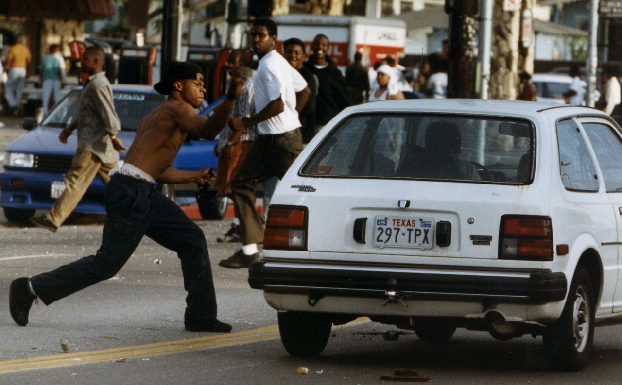 A rioter attacks a car on Florence and Normandie in Los Angeles after the Rodney King verdicts on April 29, 1992.