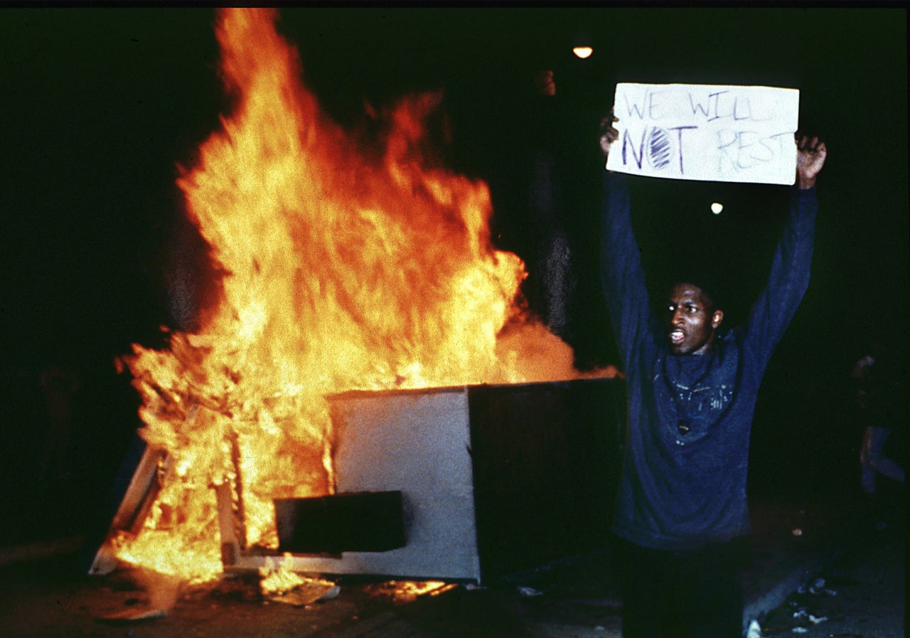 A man holds up a sign at Los Angeles City Hall to protest the Rodney King verdicts on April 29, 1992.