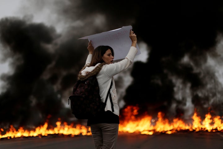 A demonstrators holds a placard in front of a burning barricade during a protest against President Michel Temer's proposal to reform Brazil's social security system in the early hours of general strike in Brasilia, Brazil, on April 28, 2017.