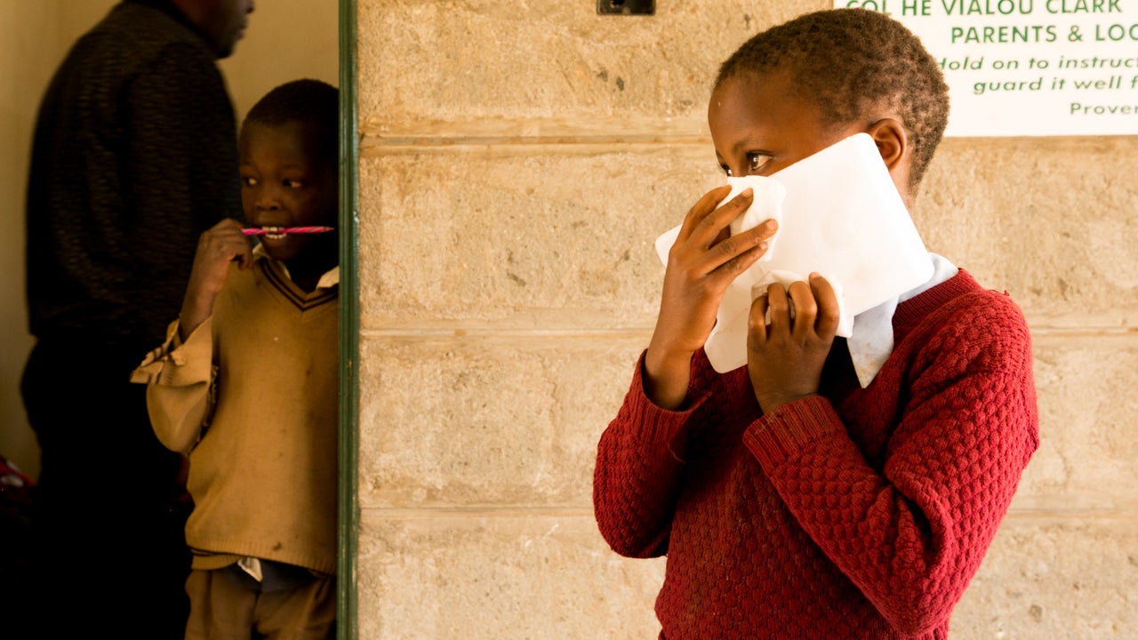 A young schoolgirl holds an ice block to her face to numb areas that will be injected with the painful treatment for cutaneous leishmaniasis at a mobile clinic in rural Kenya.