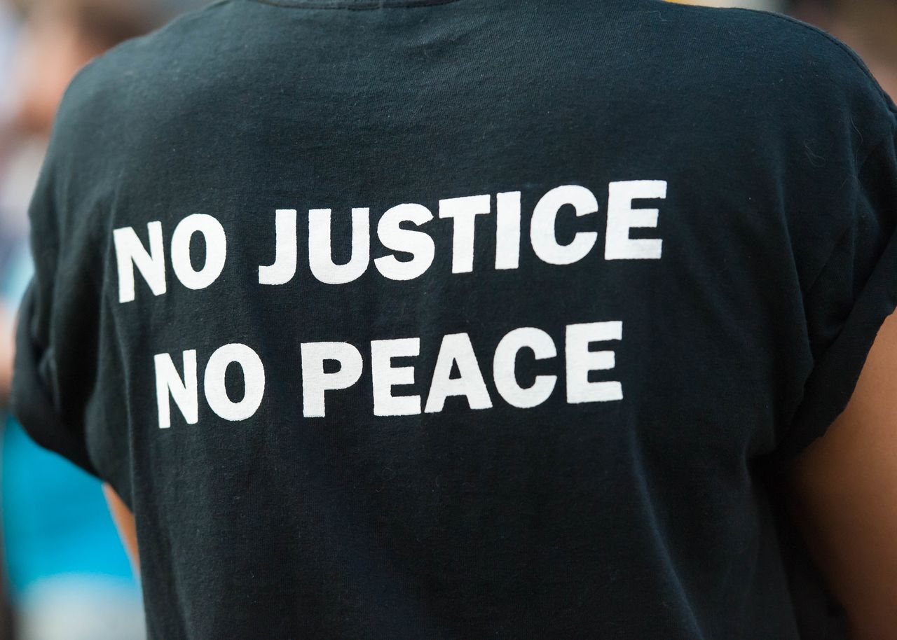 A protester wears a T-shirt proclaiming "No Justice, No Peace" as they attend a Black Lives Matter group rally.