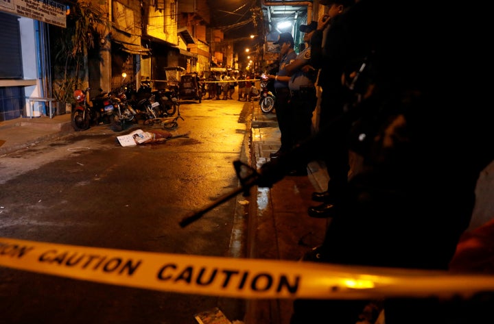 Policemen stand guard near the body of a man killed during what police said was a drug related vigilante killing in Pasig, Metro Manila.