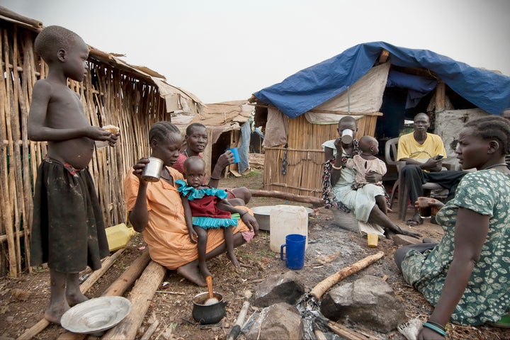 Refugees have breakfast in front of their huts in displaced persons camp, Juba, South Sudan, February 28, 2012.
