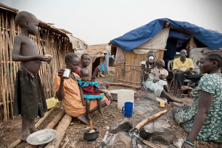 Refugees have breakfast in front of their huts in displaced persons camp, Juba, South Sudan, February 28, 2012. 