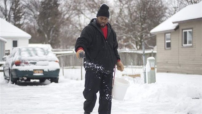 <p>Ontayveis Underwood sprinkles salt after clearing snow from a neighbor’s driveway and sidewalk in Saginaw, Michigan. Many states and cities are educating people on how much salt to use.</p>