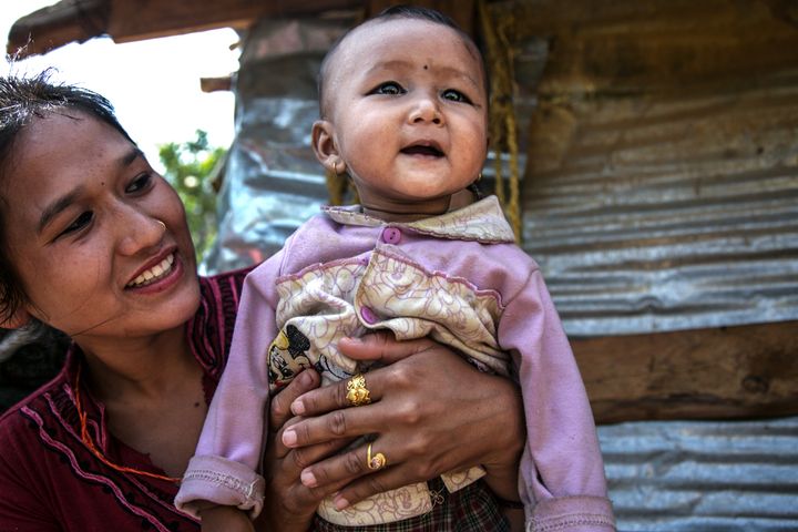A mother and her child in Chautara, Nepal, by the metal shelters they had moved into after their homes were destroyed by an earthquake.