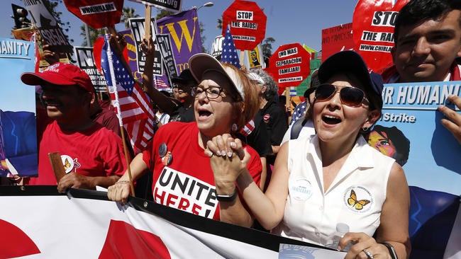 Maria Elena Durazo, center, labor leader, hold hands with immigration attorney Jessica Dominguez, right, in a May Day march