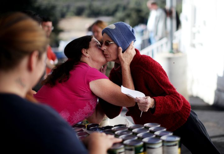 Nancy Kerr, who is suffering from cancer, gets a kiss on the cheek by volunteer Jennifer Beull-Dobbs while in line to receive donated food items from a Feeding America truck.