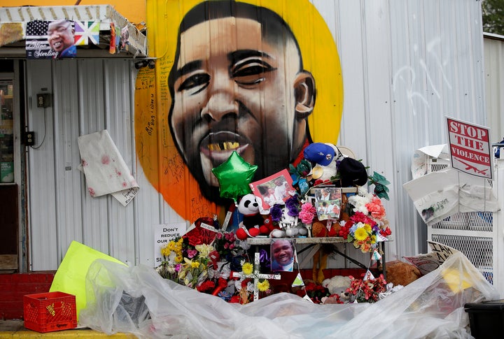 A makeshift memorial for the fatal police shooting of Alton Sterling outside the Triple S Food Mart next to a mural of Sterling July 21, 2016 in Baton Rouge, Louisiana.