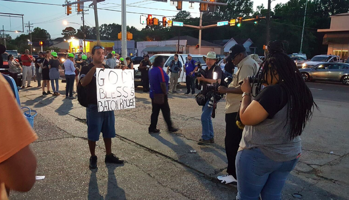 People stand gathered and holding signs on Tuesday outside of the store where Sterling was shot.