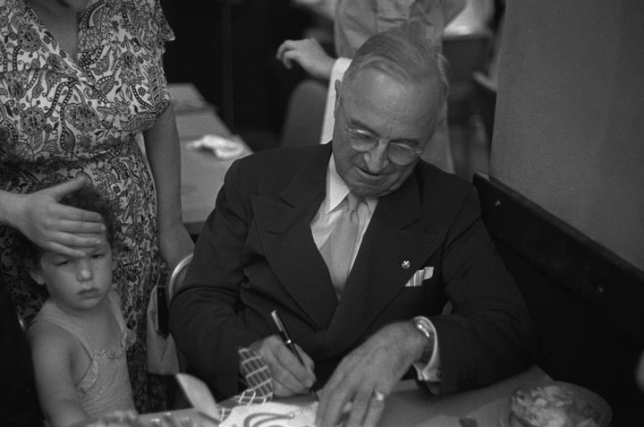 Former president Harry Truman signs a card for a young child in a restaurant. After his presidency ended in 1953, Truman retired to his hometown of Independence, Missouri.