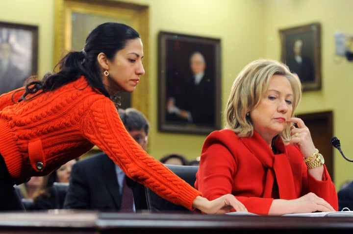 U.S. Secretary of State Hillary Clinton (R) receives a note from her aide Huma Abedin (L) as she testifies during a hearing o