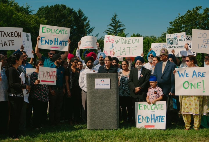 Harsimran Kaur, legal director for the Sikh Coalition, addresses a rally in response to a hate crime in Chicago suburb. Inderjit Singh Mukker, the man in the black turban to her right, was violently beaten as assailants shouted "terrorist" and "go back to your country."