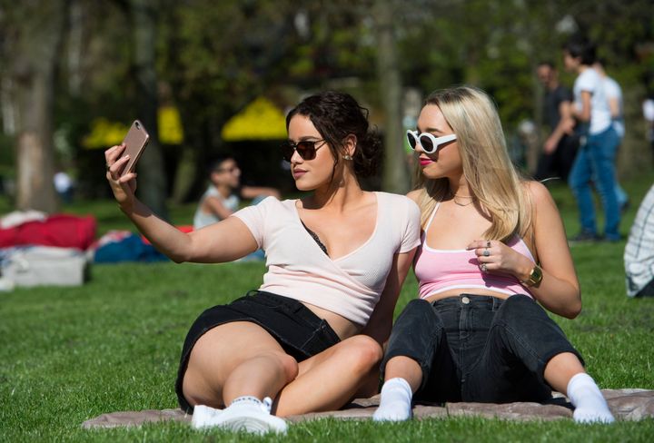 Jessica Summers (left) and Ellie Ford take a selfie while sunbathing in Hyde Park, London